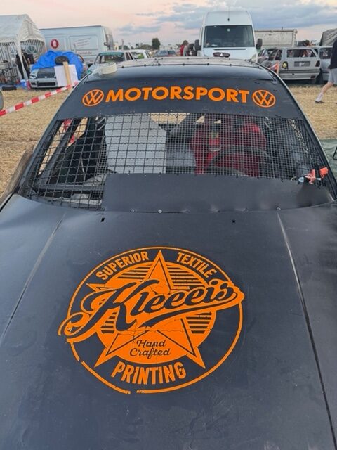 Schwarzes Motorsport Rennfahrzeug mit orangefarbenem Kleeis Logo auf der Motorhaube