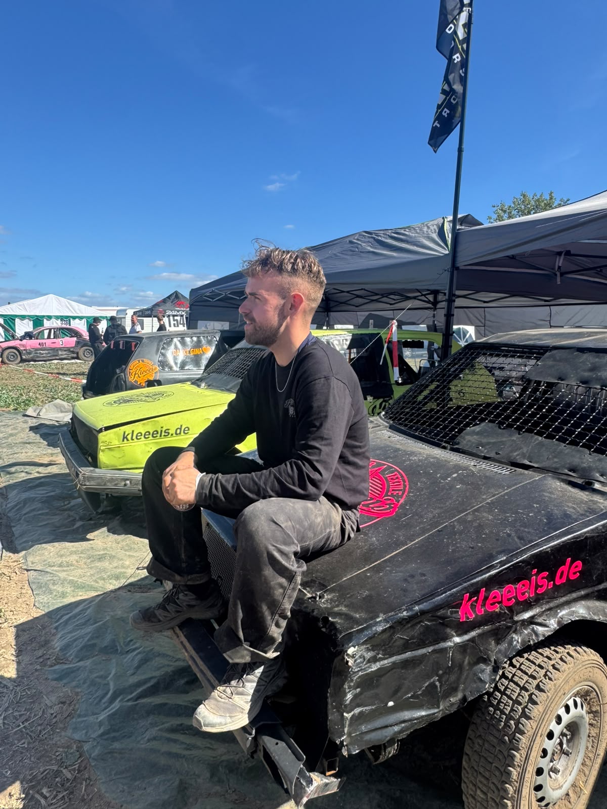 Junger Mann mit Bart sitzt nachdenklich auf einem schwarzen Stockcar