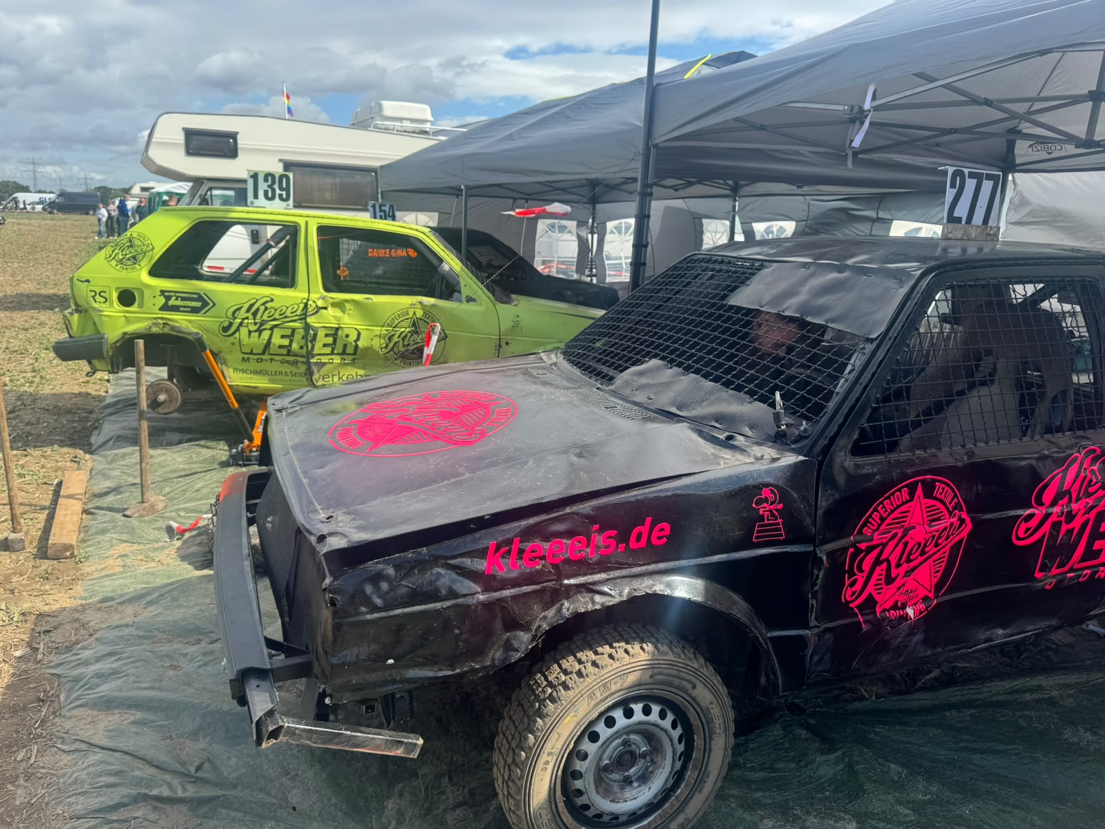 Zwei Stock Car Rennwagen in Schwarz mit Pink und Gruen bei einem Rennen