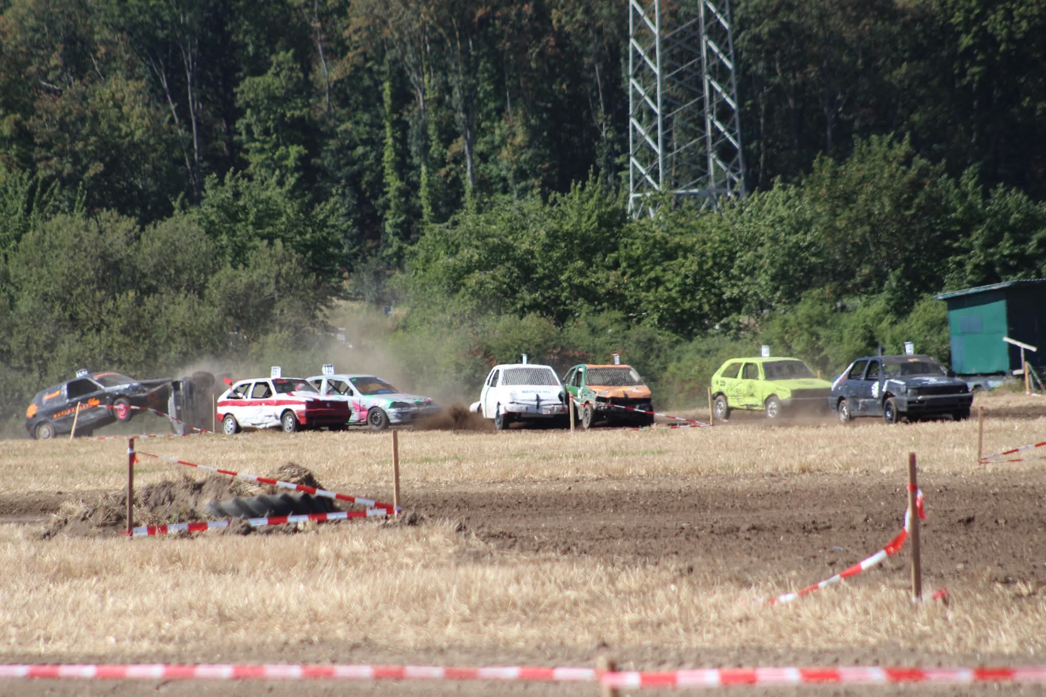 Bunte Stockcars beim Autocross Rennen auf staubiger Feldstrecke am Waldrand