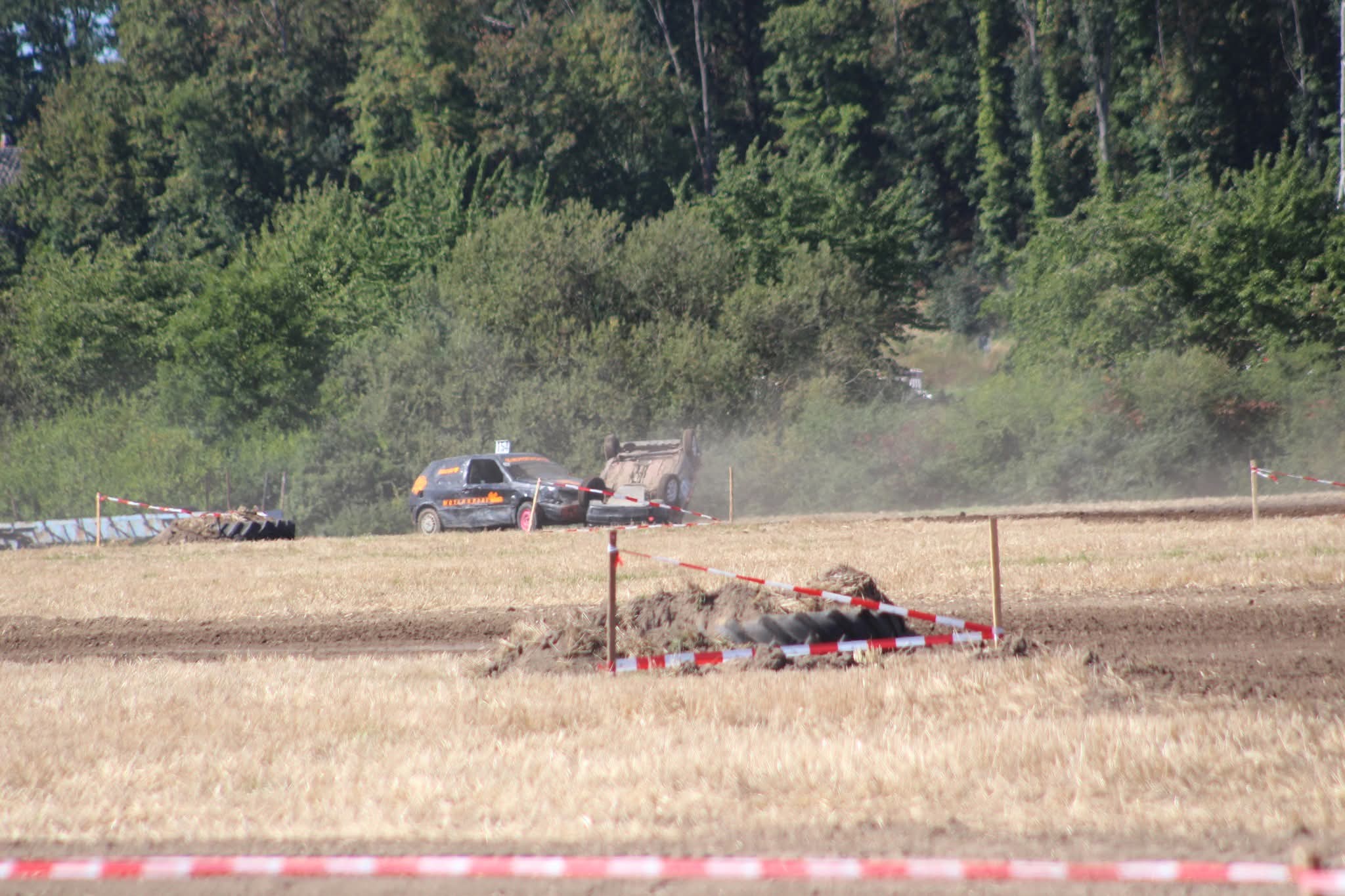 Ein umgekipptes Auto neben einem schwarzen Rennwagen bei einem Autocross Rennen