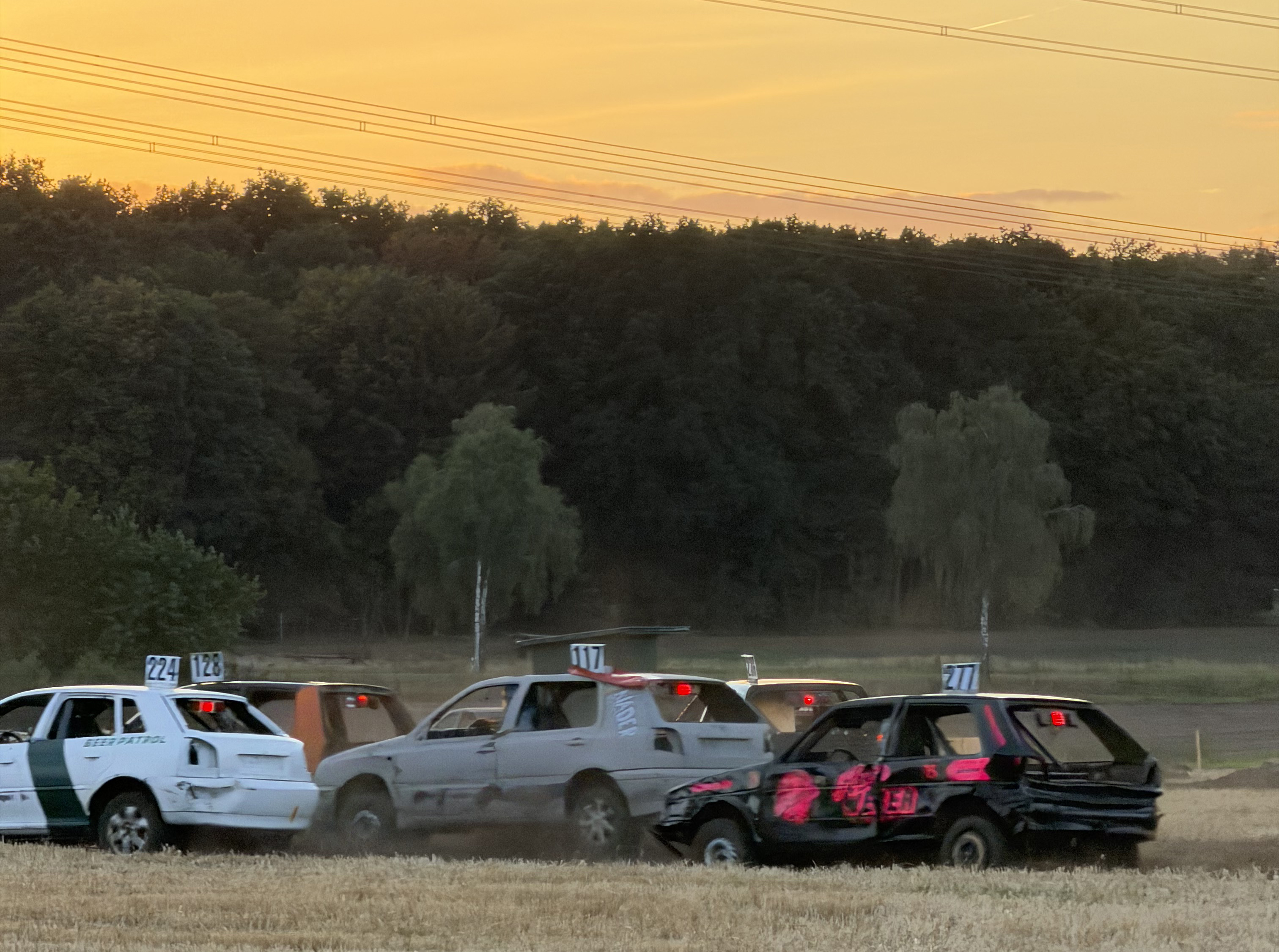 Beschaedigte Stockcar Autos mit Startnummern beim Rennen im Sonnenuntergang